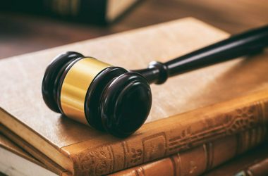 Law gavel on law books, wooden desk, dark background