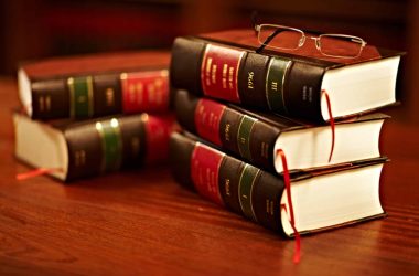 Shot of a stack of legal books and a pair of glasses on a table in a study.